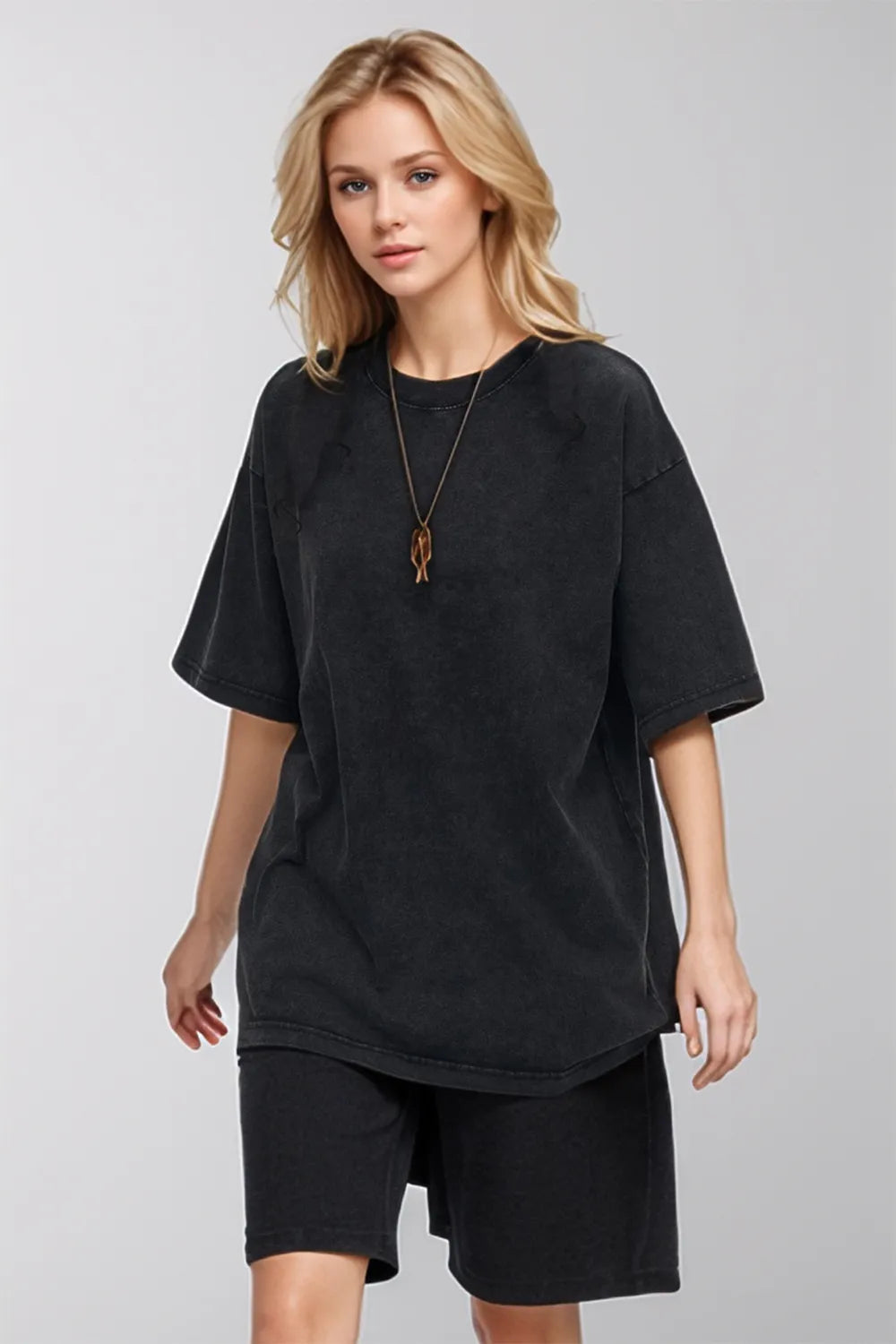 Woman wearing a black oversized t-shirt and shorts on a gray background