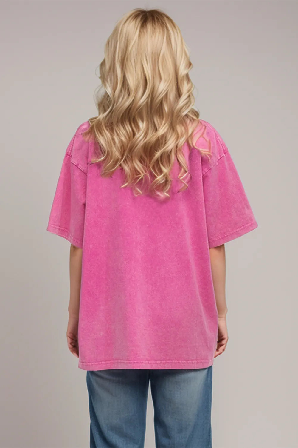 Person wearing a pink oversized shirt and blue jeans on a plain background