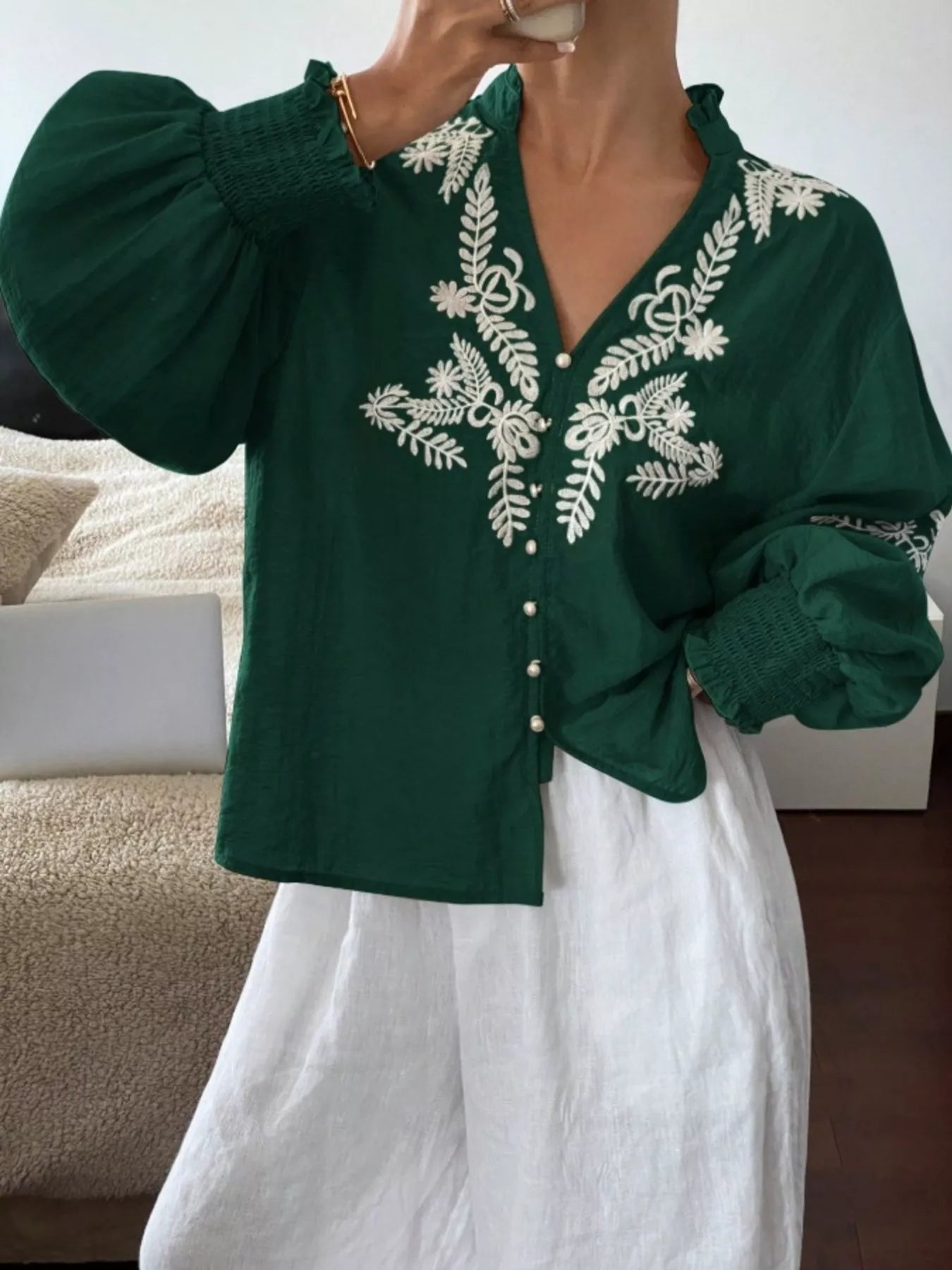 Green embroidered blouse worn by a person with a blurred background