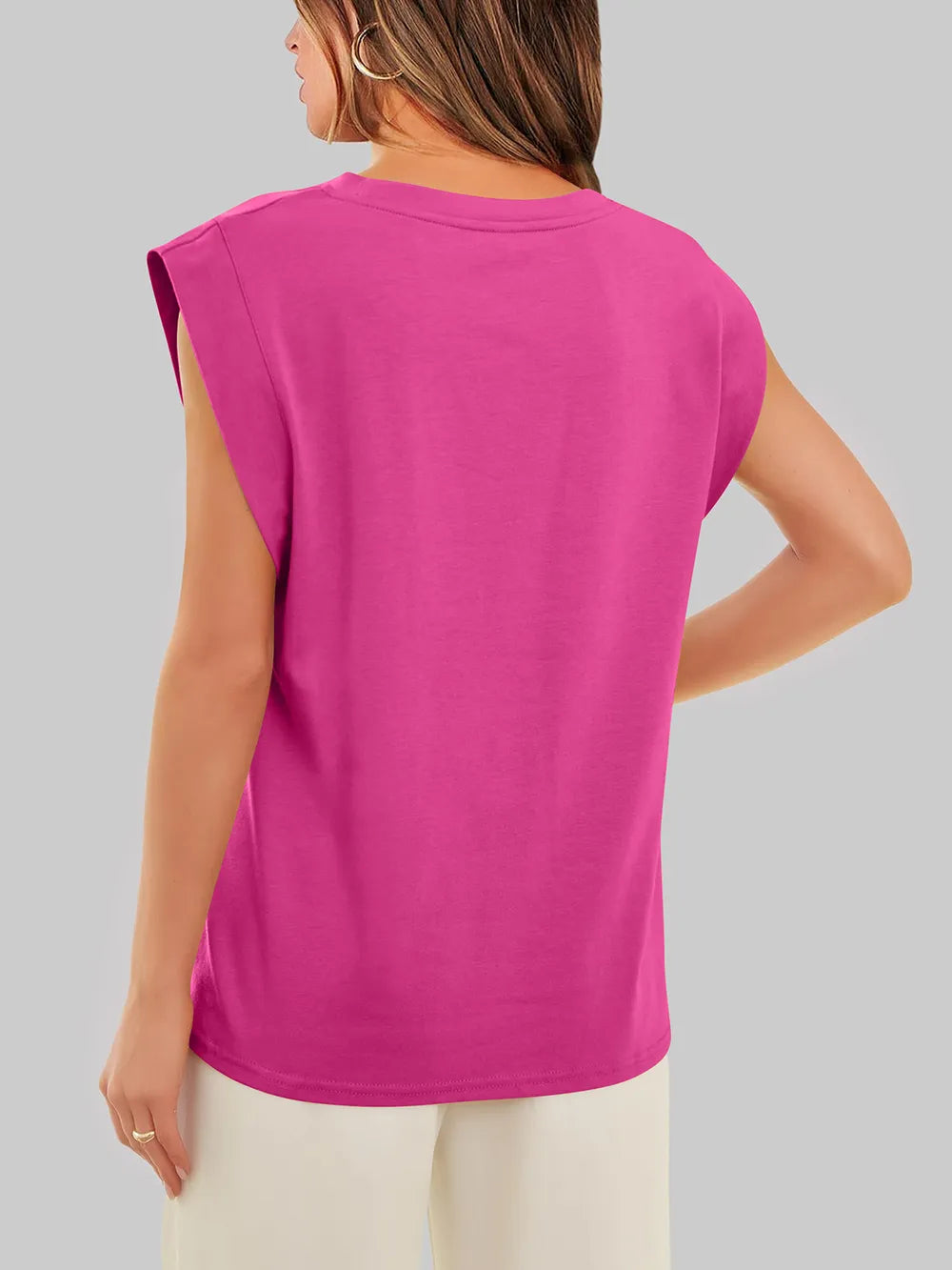 Woman wearing a bright pink sleeveless top on a gray background