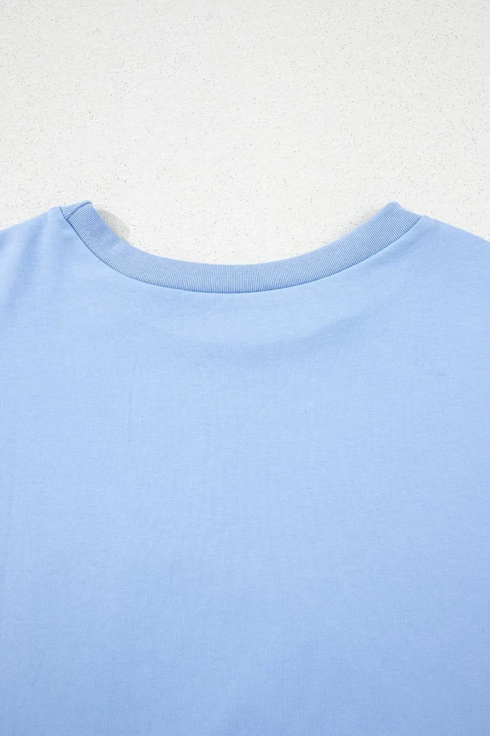 Close-up of a light blue shirt collar on a textured white background