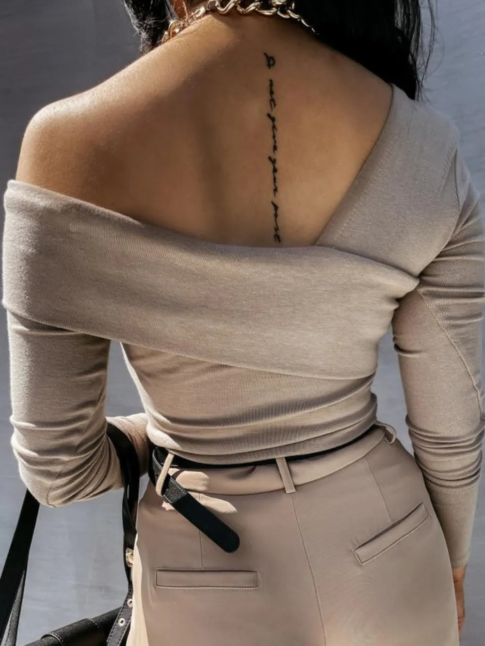 Person wearing a beige off-shoulder top and pants with a blurred background