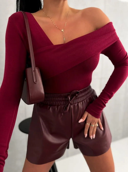 Person wearing a burgundy off-shoulder top and shorts with a matching handbag.