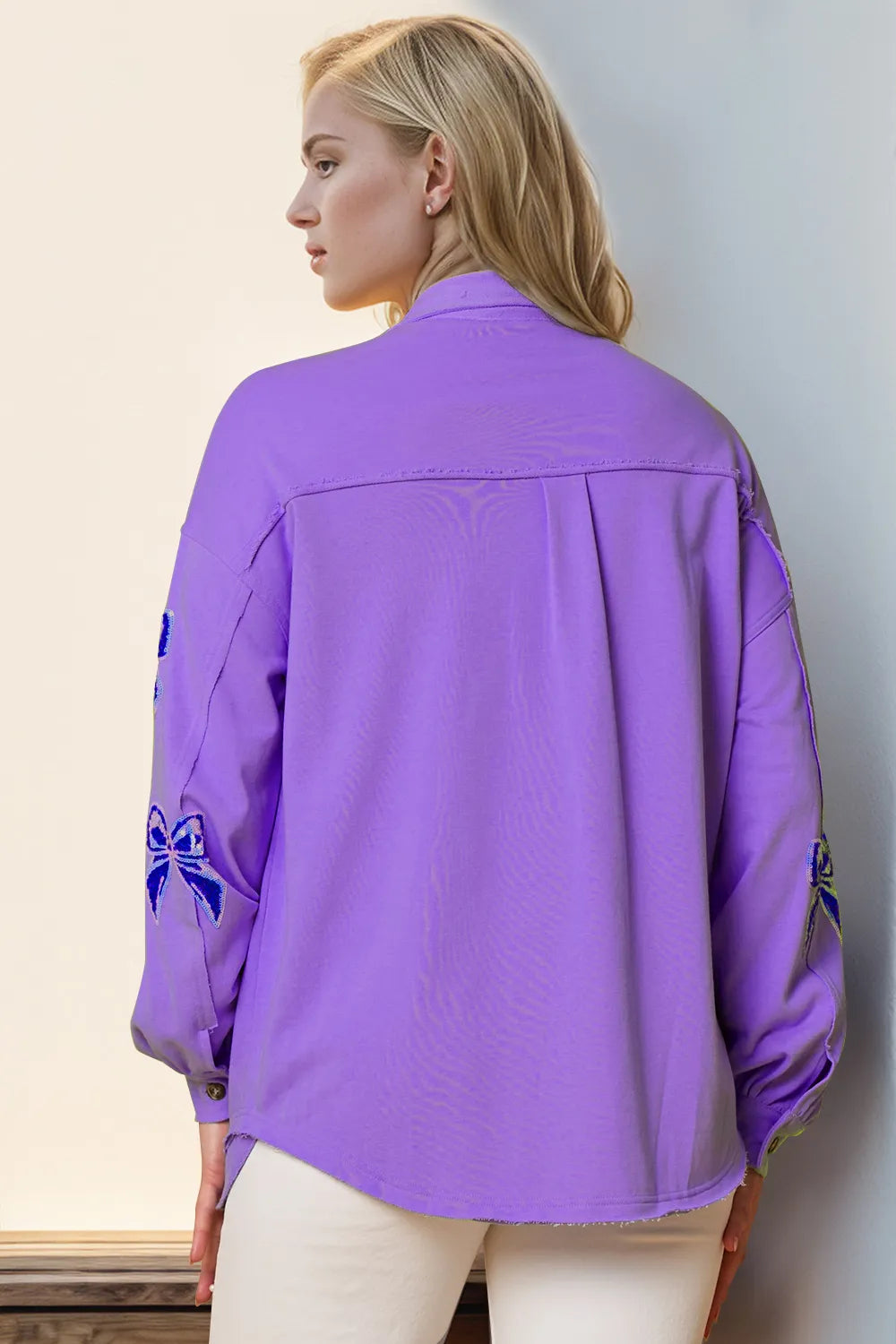 Person wearing a purple jacket with blue designs against a light background