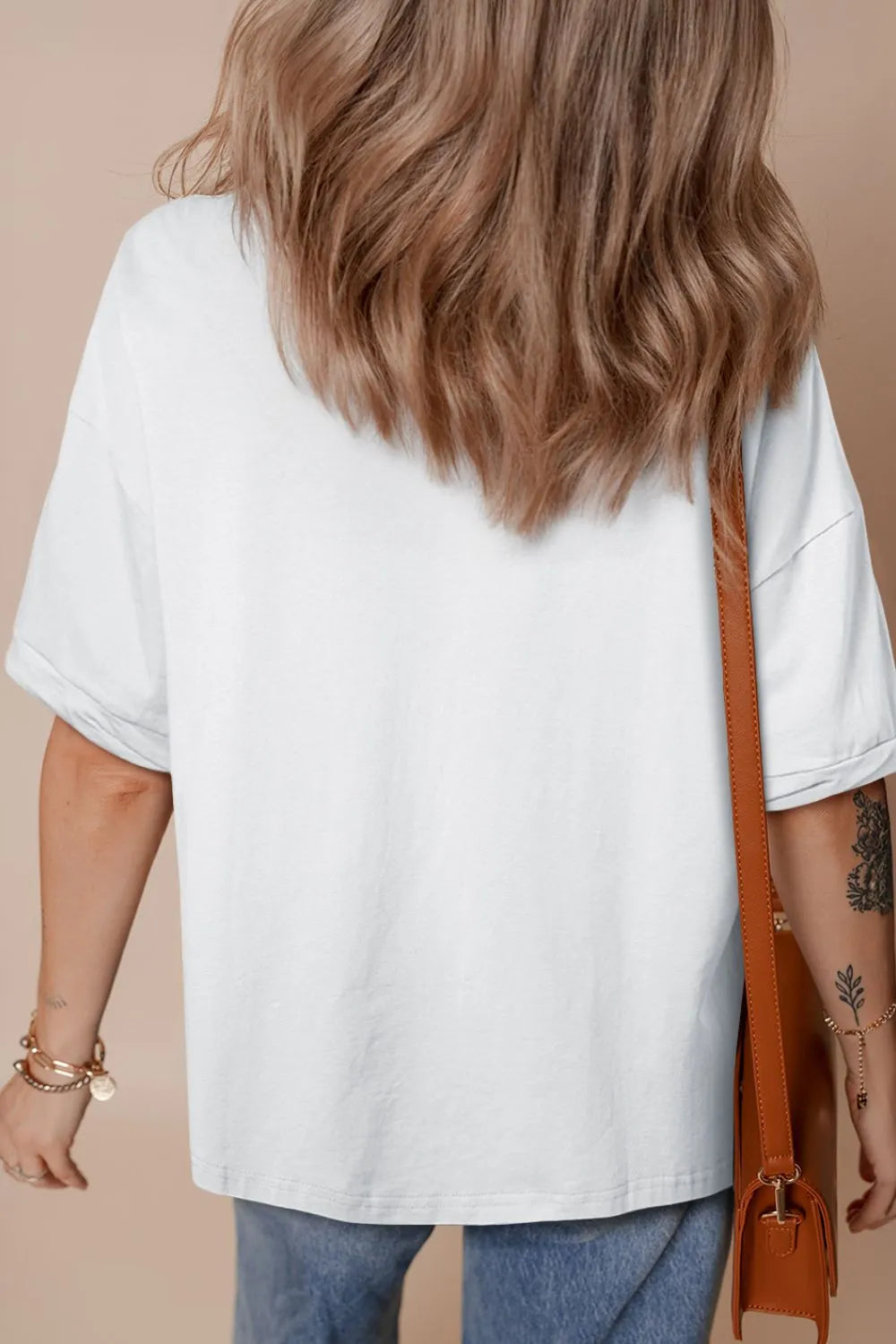 Person wearing a white oversized shirt with a brown background