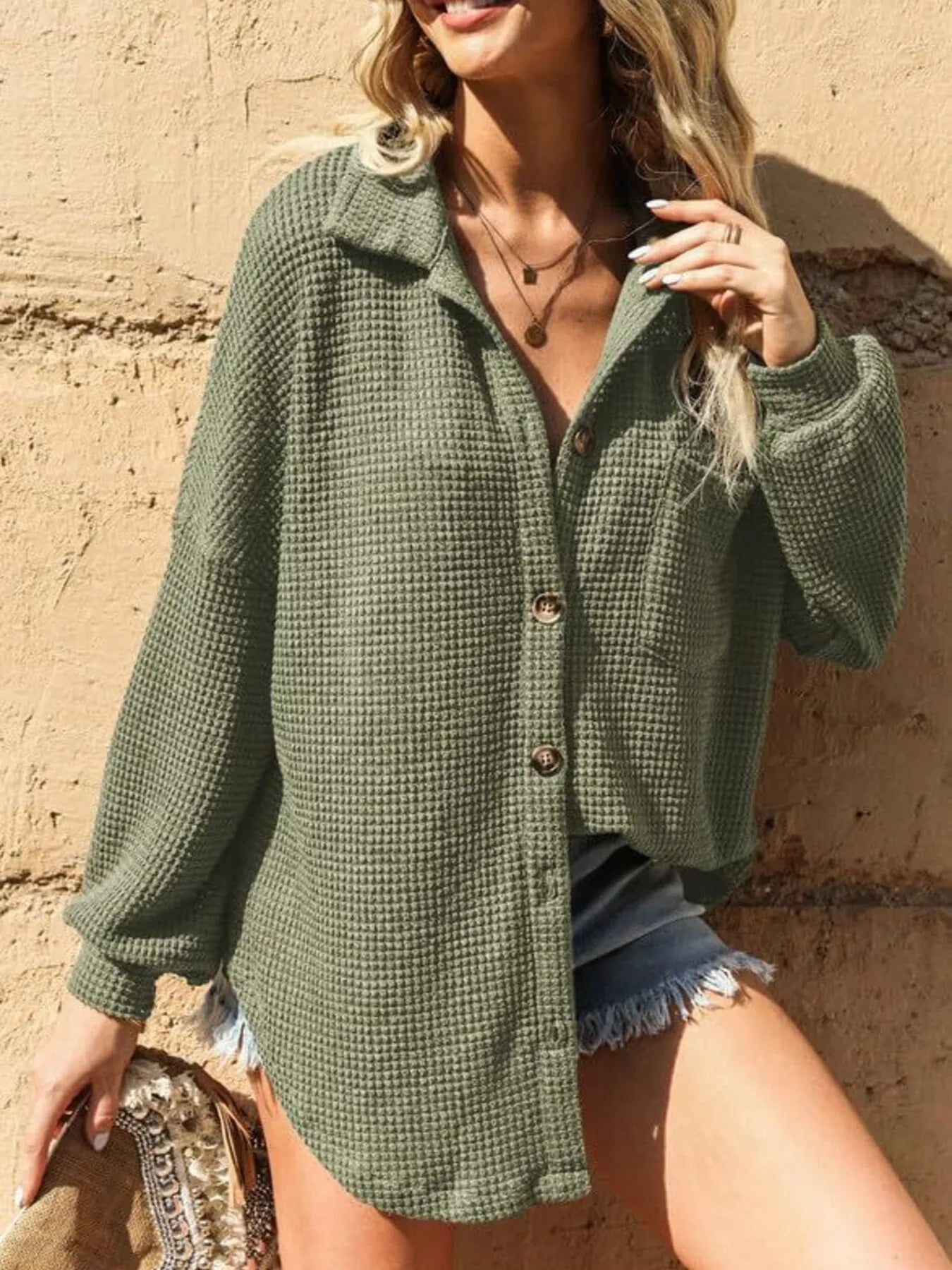 Woman wearing a green textured cardigan against a beige wall