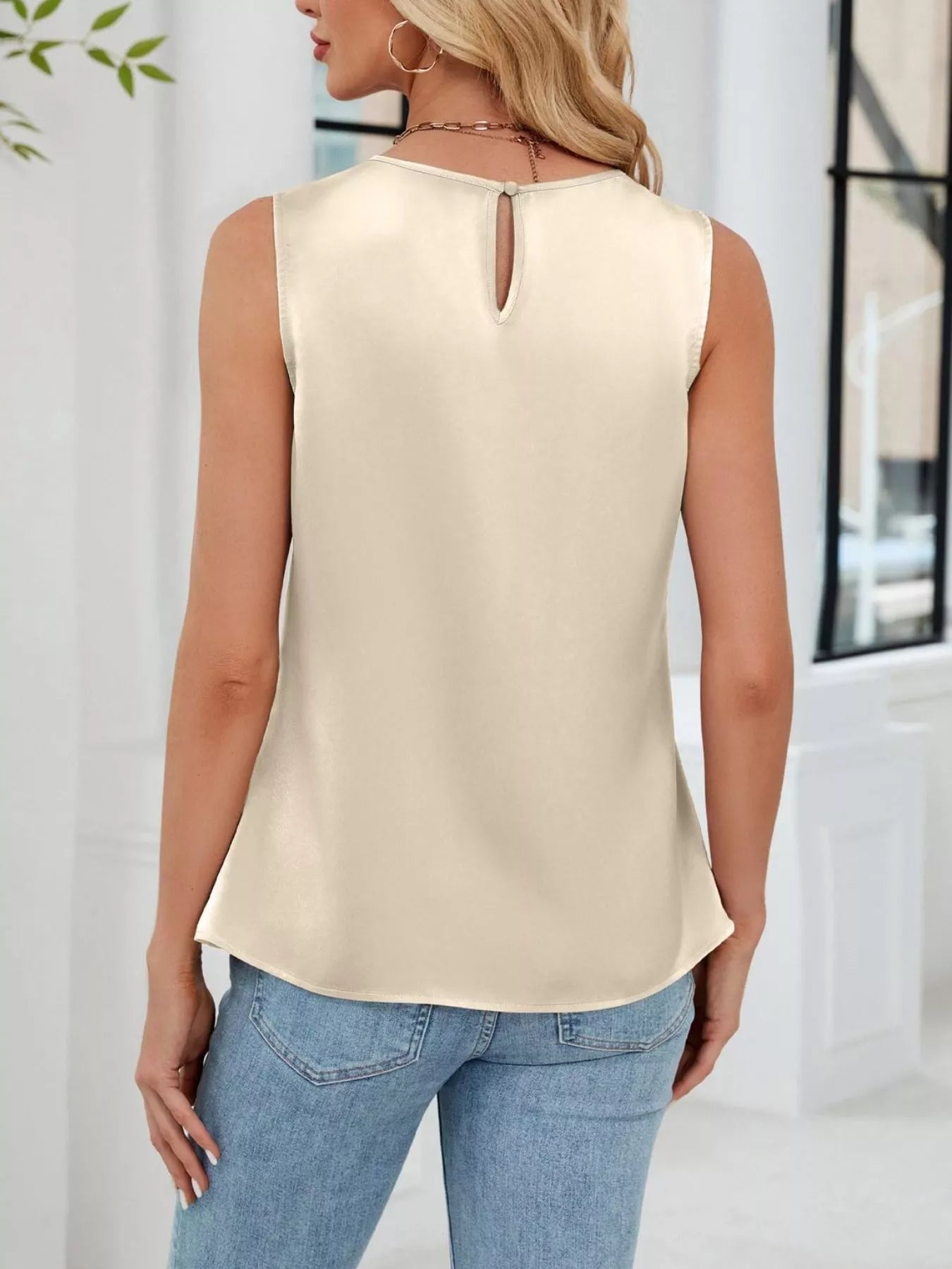 Back view of beige sleeveless blouse with flowy relaxed silhouette