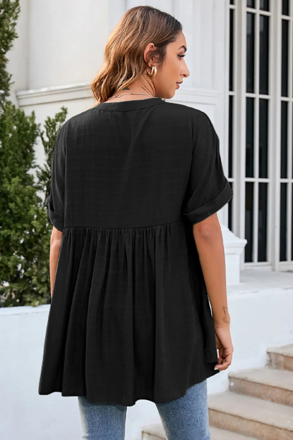 Back view of black ruched notched short sleeve blouse with flowy relaxed silhouette