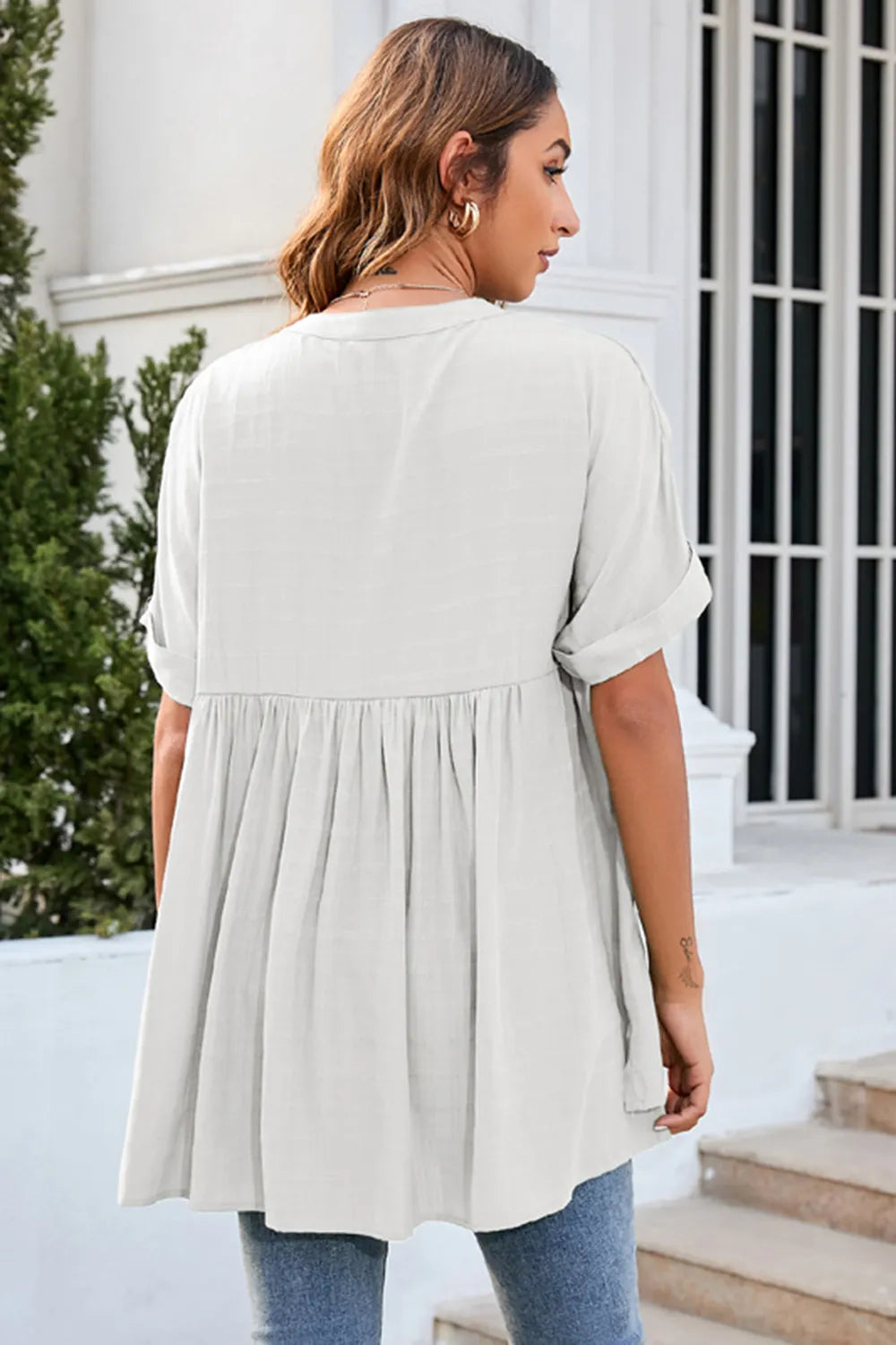 Back view of white ruched short sleeve blouse featuring loose flowing fit