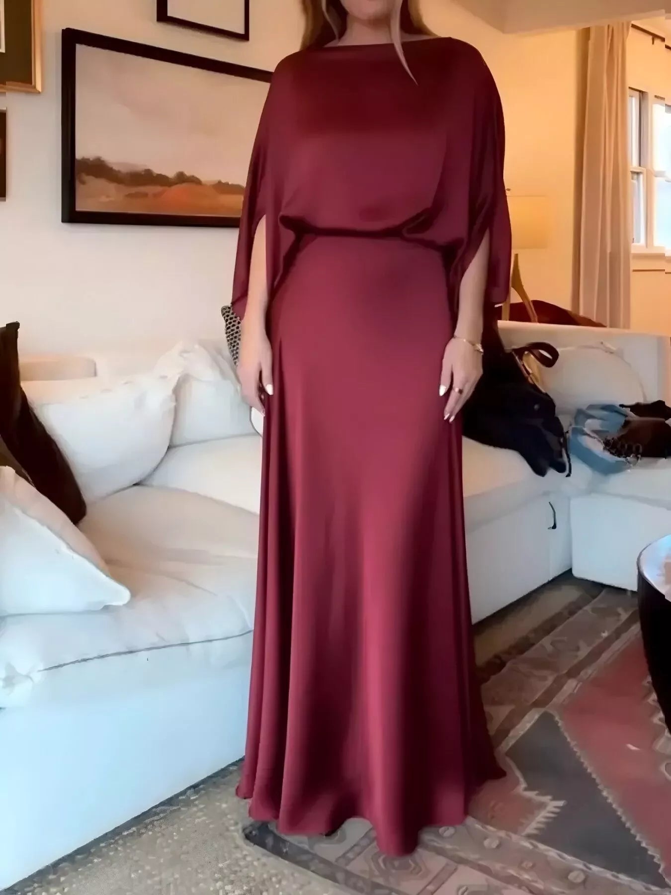 Person wearing a burgundy dress standing in a living room.