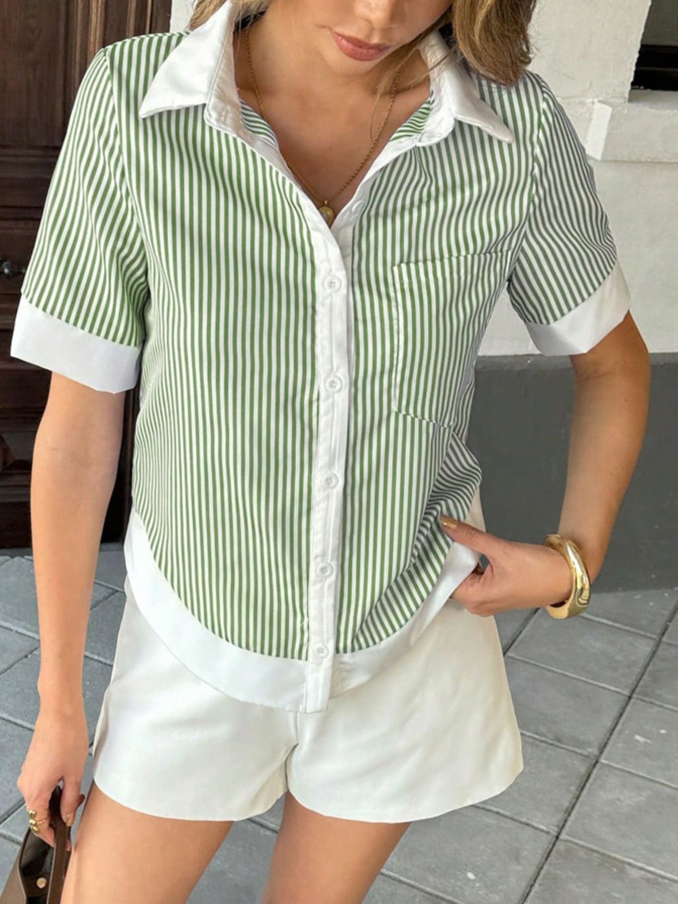 Person wearing a green and white striped shirt with white shorts, standing on a tiled floor.