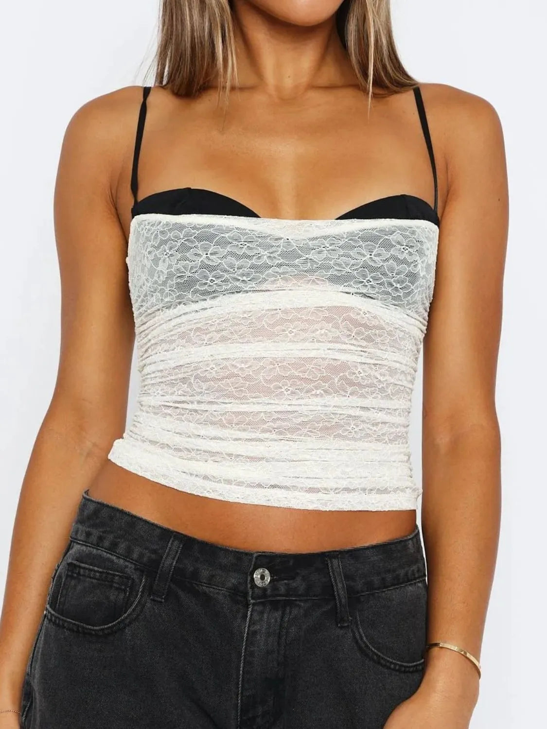 Woman wearing a white lace cami top with a sweetheart neckline, slim straps, and a fitted silhouette