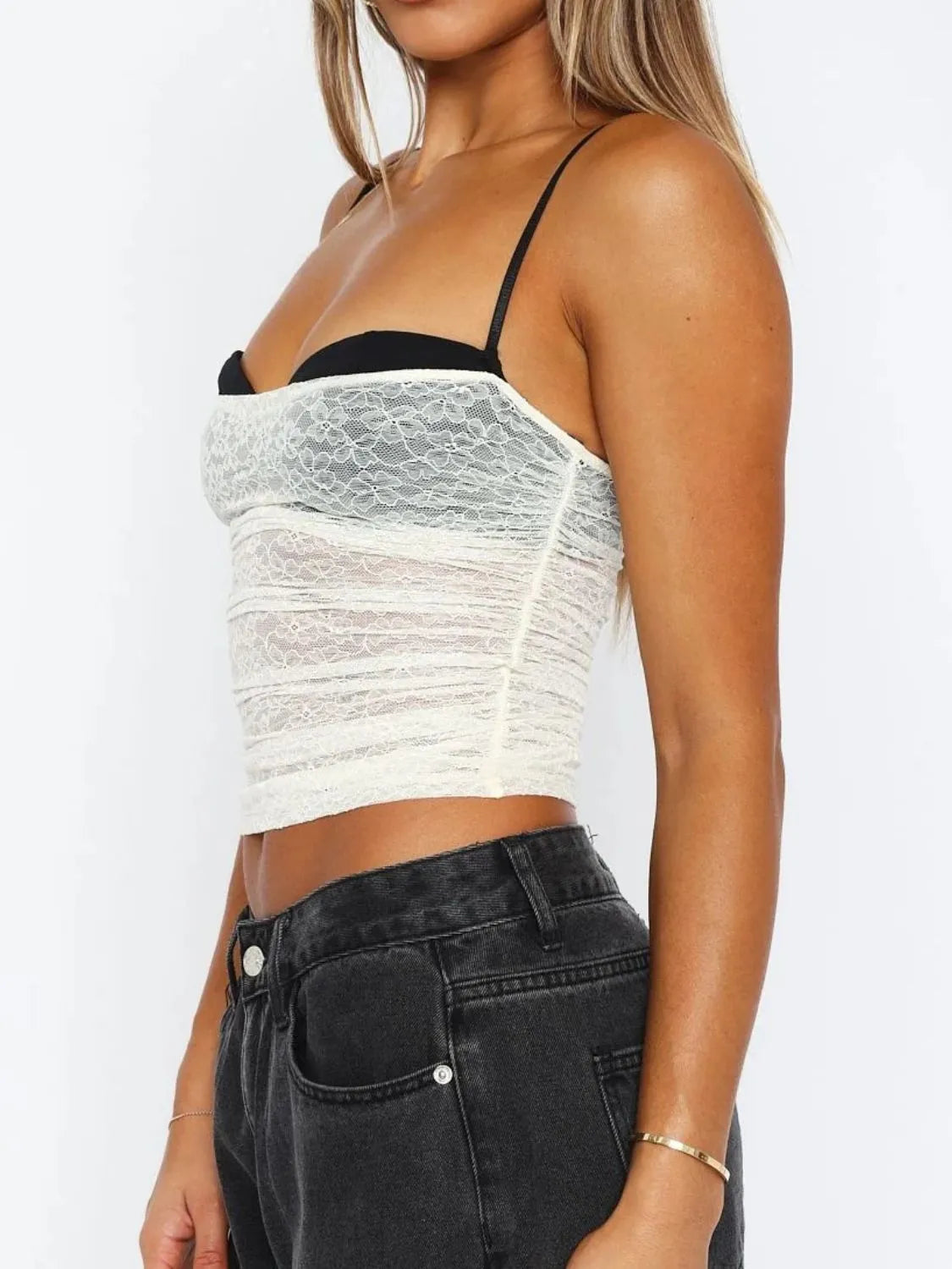 Side profile of a woman wearing a white lace cami top with a sweetheart neckline and slim shoulder straps