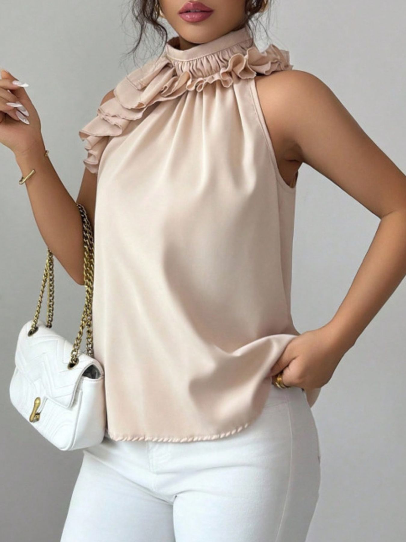 Side profile cream sleeveless top with ruffled high neckline, structured button-front