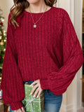 Person wearing a red sweater holding a green gift box with a Christmas tree in the background