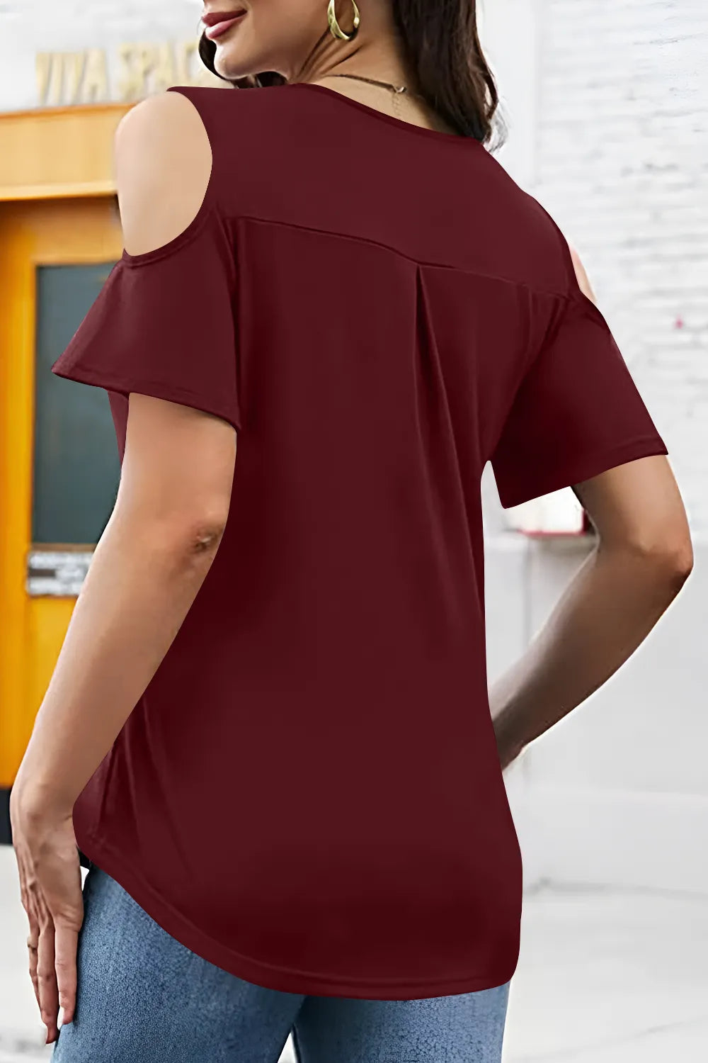 Woman wearing a burgundy off-shoulder top with a blurred background