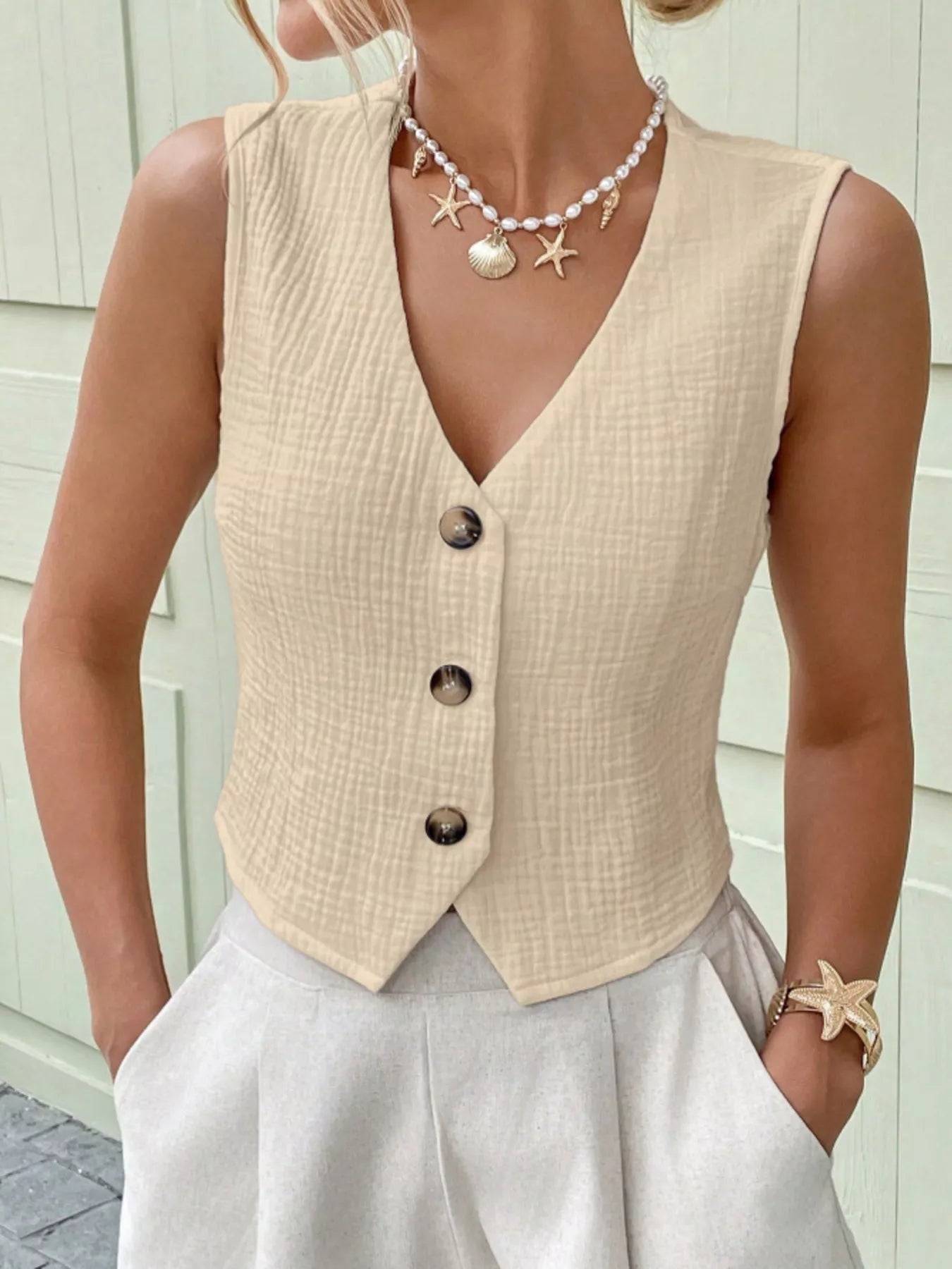 Front view of an apricot cotton vest top featuring a textured finish and contrasting buttons