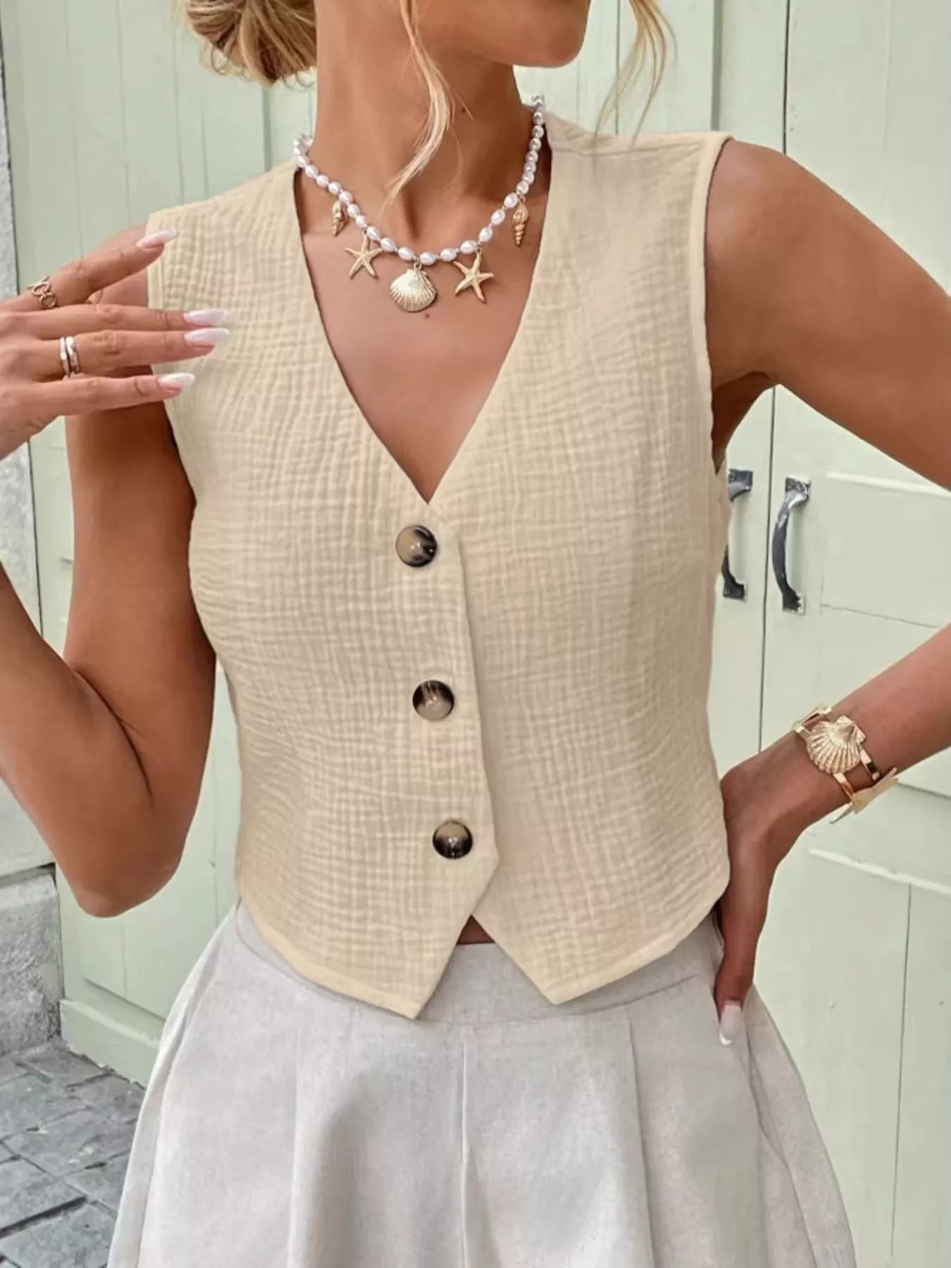 Woman wearing an apricot textured cotton vest top with button-front fastening and a sleeveless V-neck design