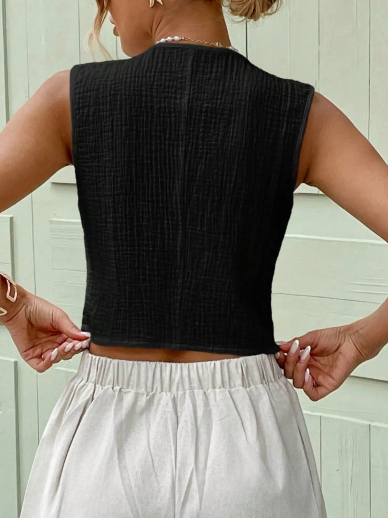 Side view of a black textured cotton vest top with a fitted sleeveless design