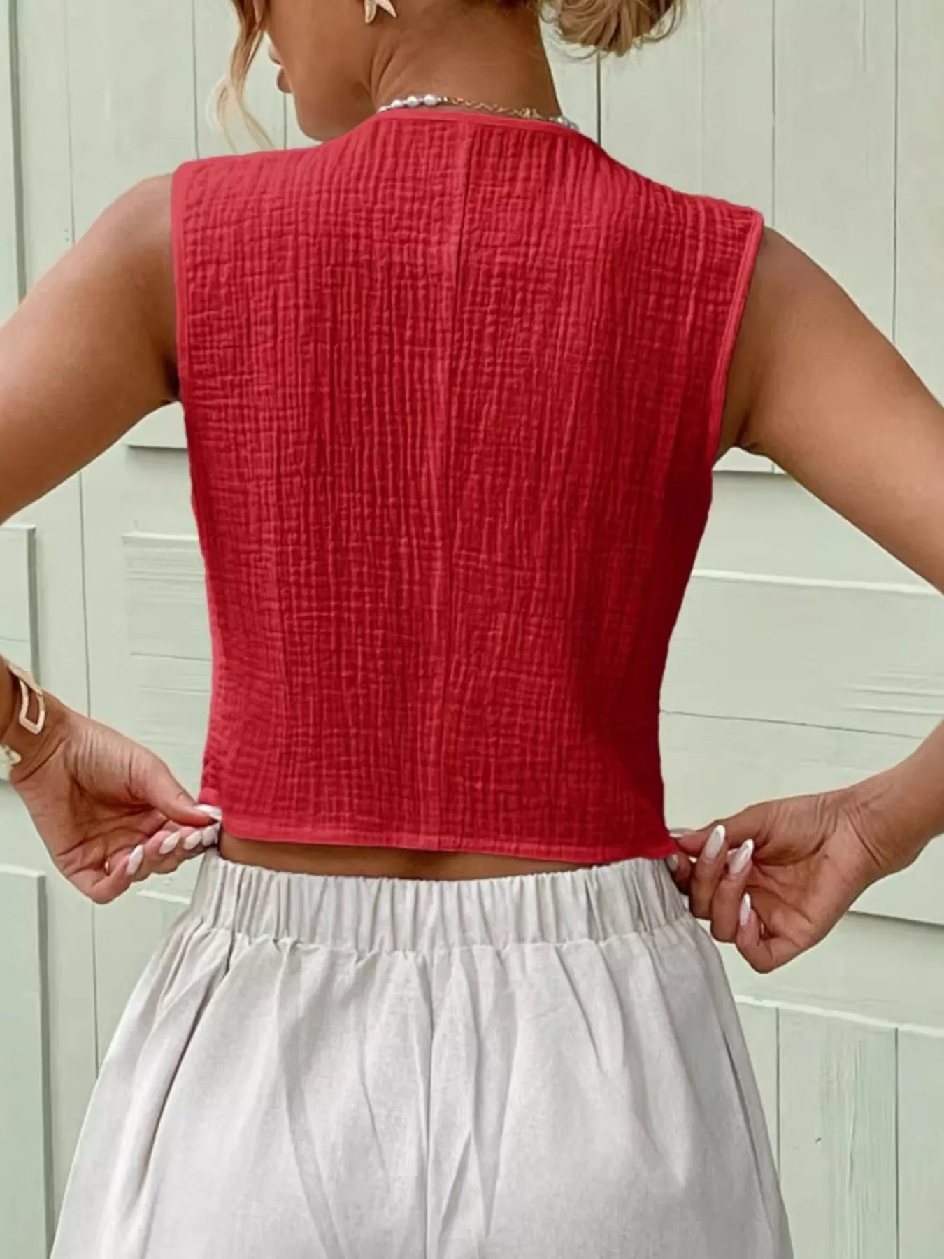 Back view of a red sleeveless cotton vest top showcasing its textured finish and simple design