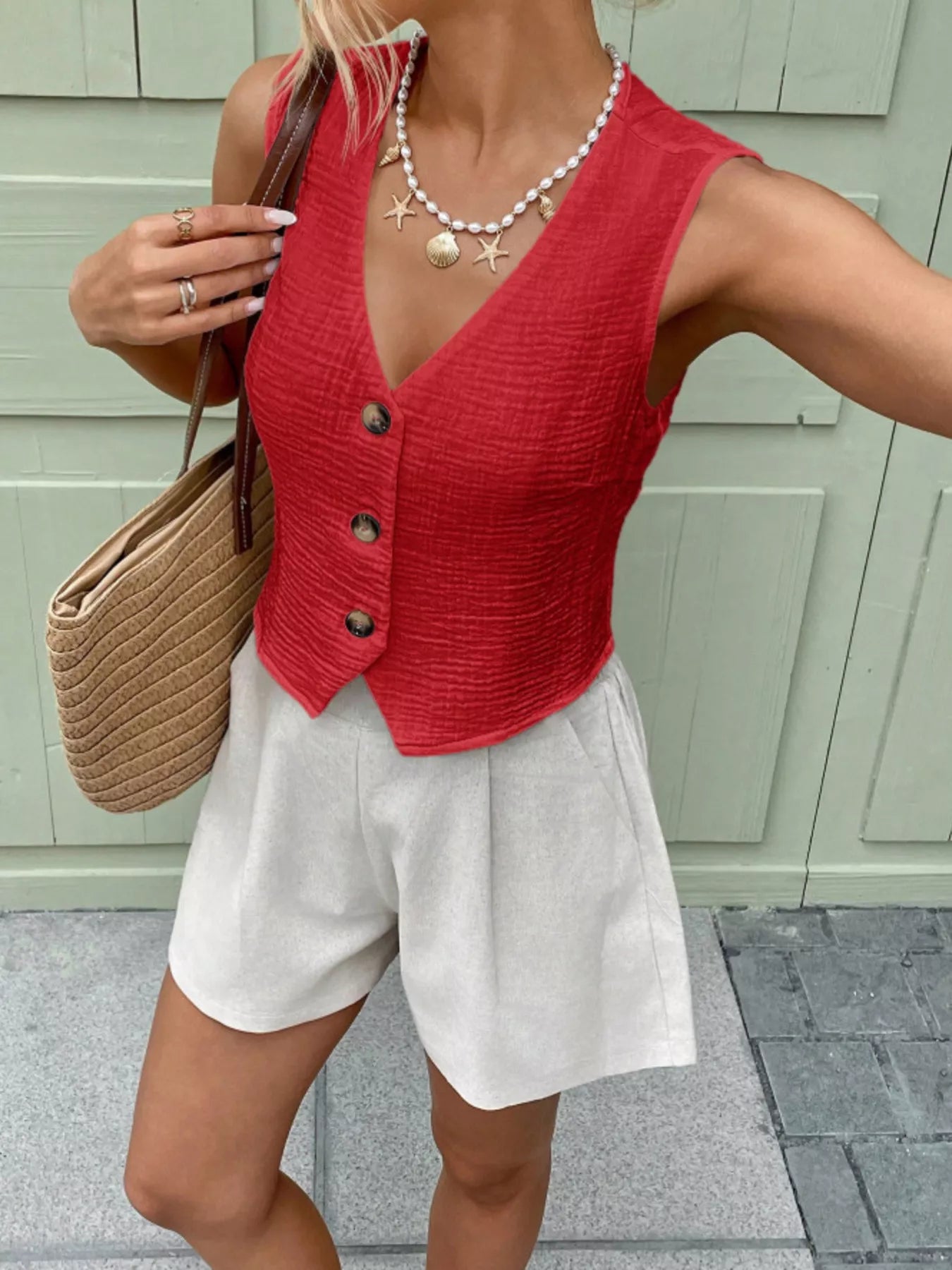 Front view of a red sleeveless cotton vest top featuring textured material and decorative buttons