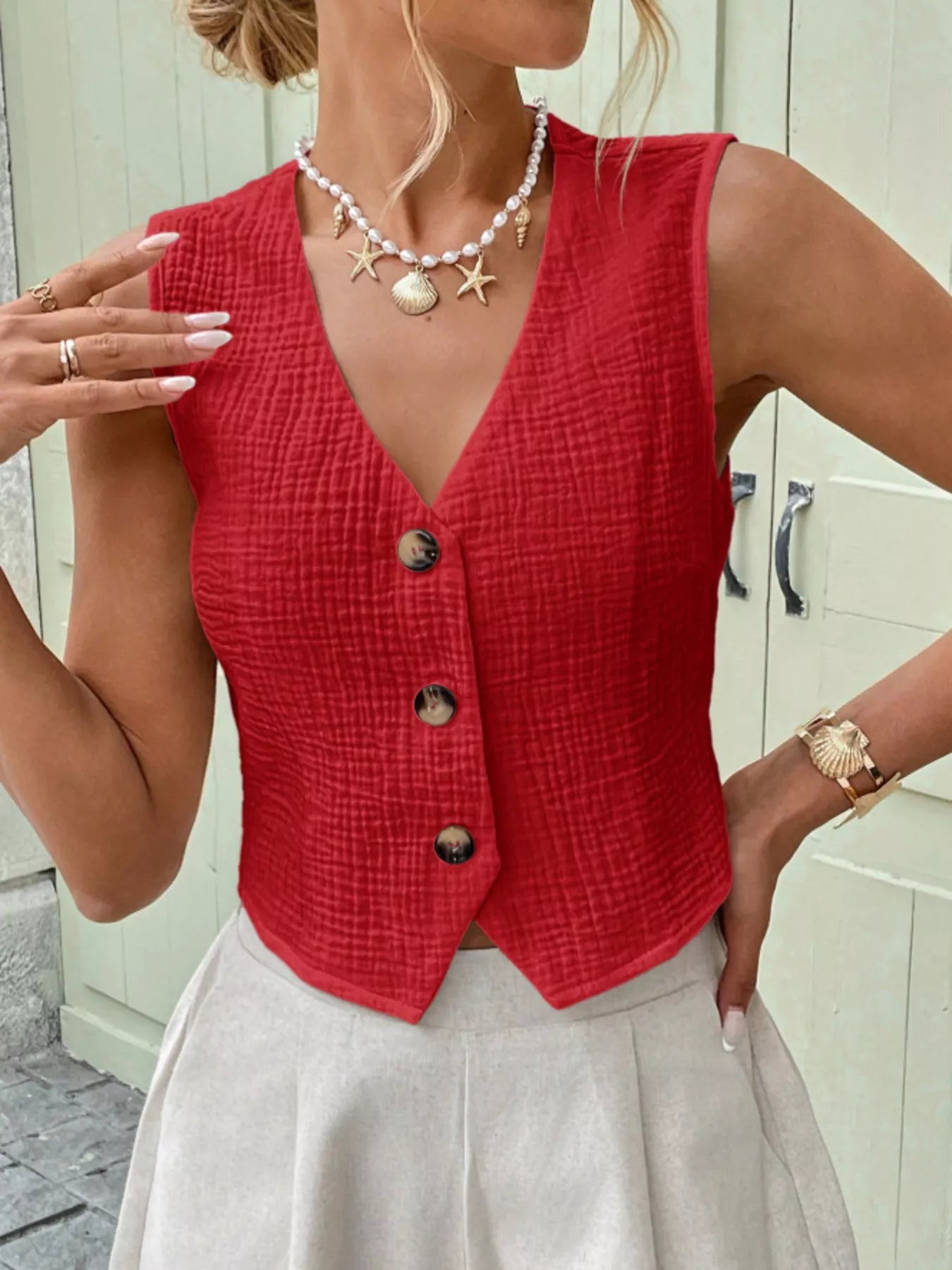 Woman wearing a red textured cotton vest top with a button-front closure and sleeveless cut
